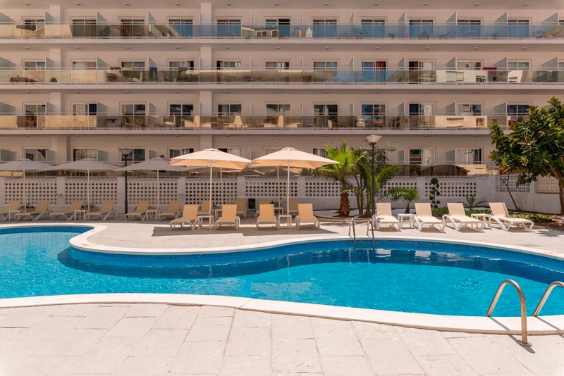 Piscina con solárium en Salou, equipada con tumbonas y sombrillas.